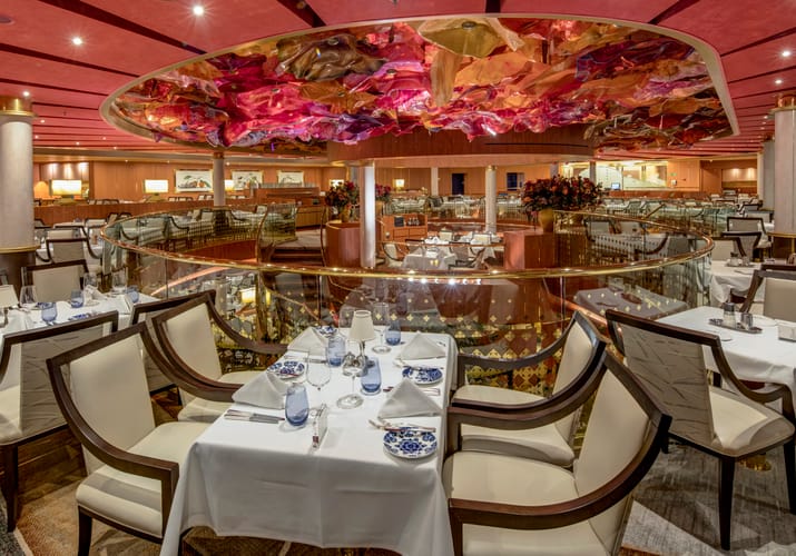 Elegant hovedrestaurant p&aring; MS Westerdam med hvide duge, d&aelig;kkede borde og kunstnerisk loftsdekoration