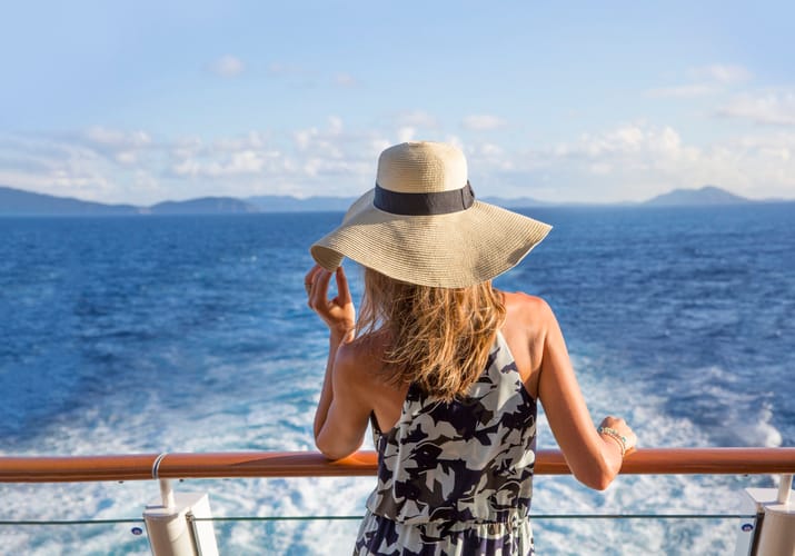 Kvinde med hat ved rælingen ombord på Norwegian Escape krydstogtskibet – dag på havet
