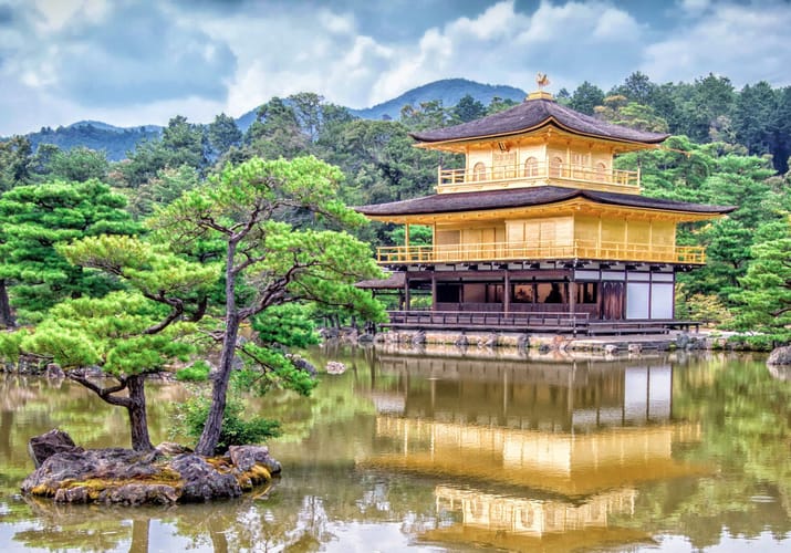 Kinkaku-ji det gyldne tempel i Kyoto omgivet af gr&oslash;nne tr&aelig;er og reflekteret i tempels&oslash;en