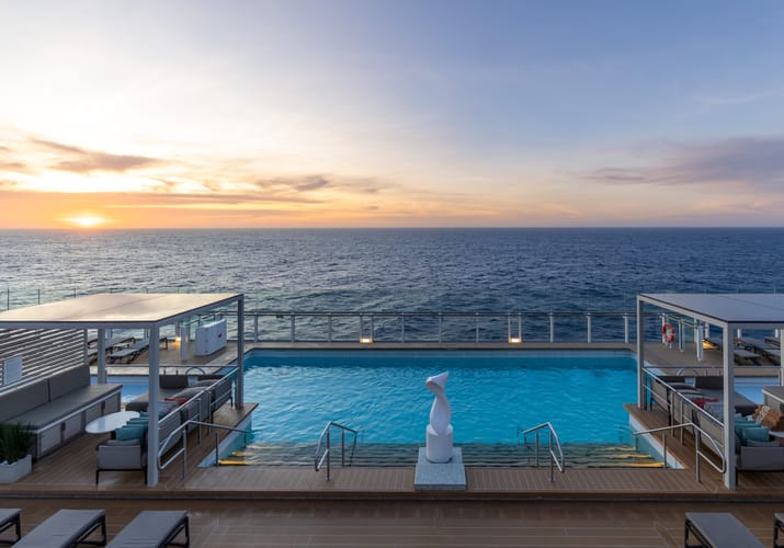 Pooldæk med infinitypool og loungemøbler på Silversea-skib ved solnedgang over havet