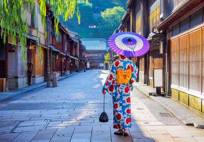 Person i farverig kimono med parasol g&aring;r gennem traditionel gade i Kanazawa i Japan