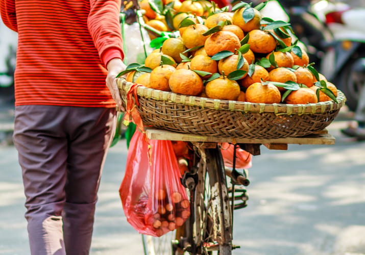 kvinde går med cykel med appelsiner